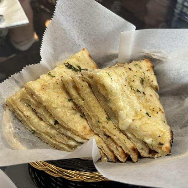 Warm, cheesy naan bread, cut into triangles and served in a basket lined with parchment paper.