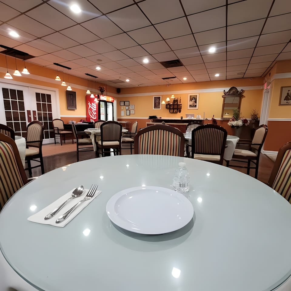 A restaurant dining room with orange walls, set tables, and a Coca-Cola cooler in the background.