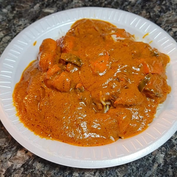 Spice Rack's chicken tikka masala with rice, served on a white plate.